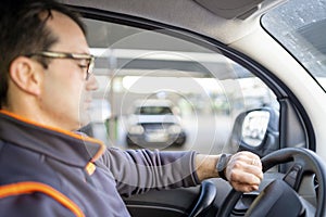 A man driving a car and looking on the watch