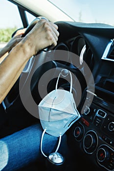 Man driving car and mask hanging on the dashboard
