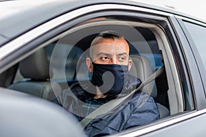 man driving a car puts on a black mask