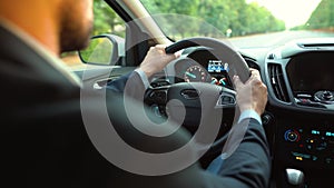 Man driving a car on the road in sunny weather. View from behind the driver