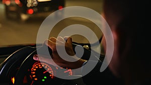 Man driving car through the streets of evening city. Cropped. Right hand drive car. Traveling, trip, night life concept