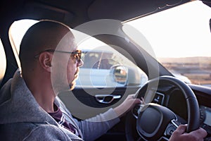 Man driving a car. Success in motion. Handsome young man driving a car. A man holds the steering wheel of a car