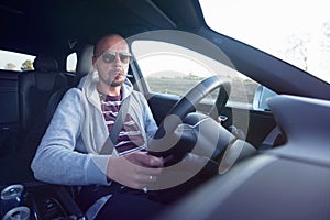 Man driving a car. Success in motion. Handsome young man driving a car. A man holds the steering wheel of a car