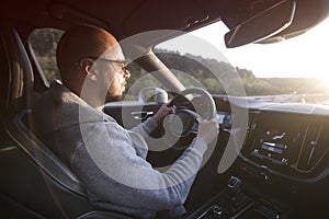 Man driving a car. Success in motion. Handsome young man driving a car. A man holds the steering wheel of a car