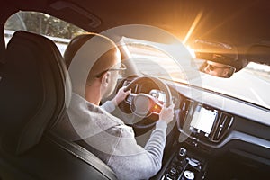 Man driving a car. Success in motion. Handsome young man driving a car. A man holds the steering wheel of a car