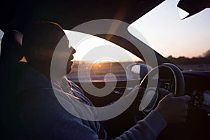 Man driving a car. Success in motion. Handsome young man driving a car. A man holds the steering wheel of a car