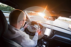 Man driving a car. Success in motion. Handsome young man driving a car. A man holds the steering wheel of a car