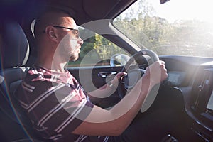 Man driving a car. Success in motion. Handsome young man driving a car. A man holds the steering wheel of a car