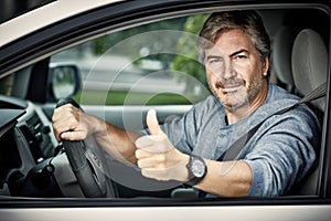 Man driving car with thumb.