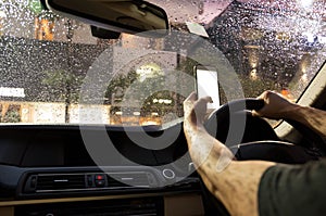 Man driving car and using cell phone while raining at night