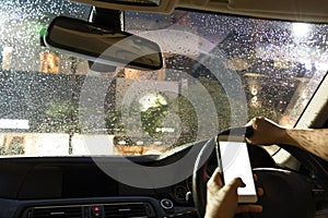 Man driving car and using cell phone while raining at night
