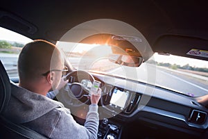 Man driving car using mobile phone texting message or calling..Driver holding smart phone while driving car on the road..People