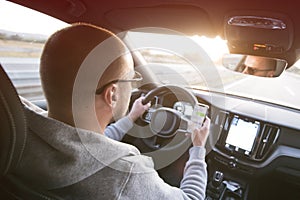 Man driving car using mobile phone texting message or calling..Driver holding smart phone while driving car on the road..People