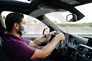 Man driving a car wearing on a medical mask during a Covid-19 pandemic