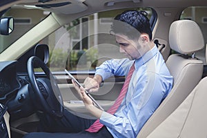 Man driving checks digital tablet for locating an address