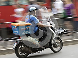 Man driving delivery scooter in city traffic