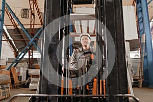 Man driving a forklift through a warehouse in a factory. driver in uniform and protective helmet. the concept of