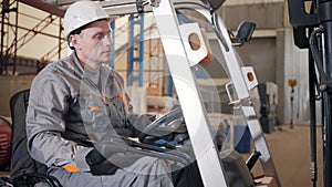 Man driving a forklift through a warehouse in a factory. driver in uniform and protective helmet. the concept of