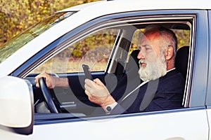 Man driving his car and looking at smartphone