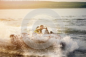 A man driving a jet ski , stunting and making spray of water drops with a sunlight on background photo