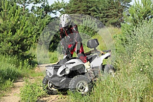 Man driving modern quad bike on sandy road near forest. Extreme sport