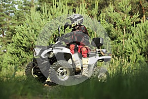 Man driving modern quad bike on sandy road near forest. Extreme sport