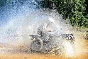 Man driving motocross ATV quad through splashing river lake water with high speed. Foy, Foyross Lake, Sudbury, Canada.