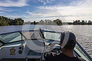 Man driving a motorboat on a tranquil lake at Laguna del Tesoro in Guama, Matanzas, Cuba photo