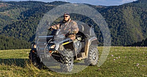 A man driving a quad ATV motorcycle through beautiful meadow landscapes