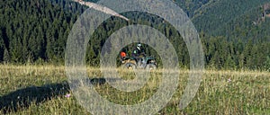 A man driving a quad ATV motorcycle through beautiful meadow landscapes