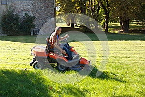 Man driving a red lawn mower (tractor)