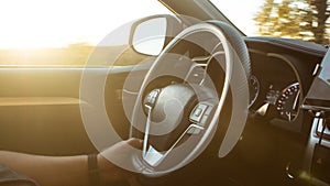 Man is driving vehicle with sun flare from the outside in the sunny day. Hand holding car steering wheel. View of man on road trip