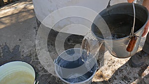 Man drops chain with bucket into rustic well to draw water.