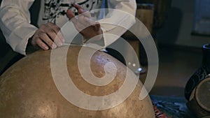 Man drumming out a beat on an arabic percussion drum named Calabasse at home.