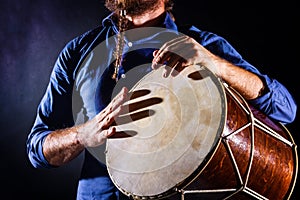 Man is drumming on wooden ethnic drum