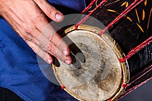 Man is drumming on wooden ethnic drum