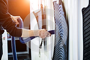 Man drying car carpet with vacuum cleaner after washing