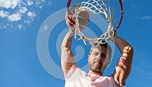 man dunking basketball ball through net ring with hands, copy space, male basketball