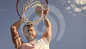 man dunking basketball ball through net ring with hands, copy space, male basketball