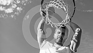 man dunking basketball ball through net ring with hands, copy space, male basketball