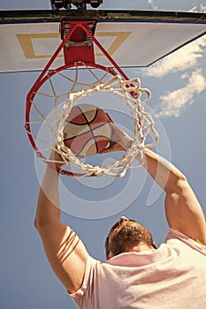 man dunking basketball ball through net ring with hands, sport success