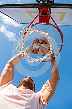 man dunking basketball ball through net ring with hands, sport success