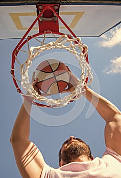 man dunking basketball ball through net ring with hands, success