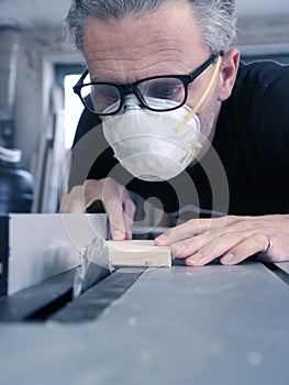 Man with a dust mask and goggles working on a circular saw