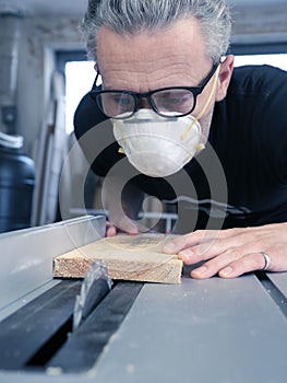 Man with a dust mask and goggles working on a circular saw