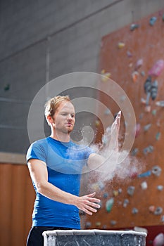 Man dusting powder by climbing wall in crossfit gym