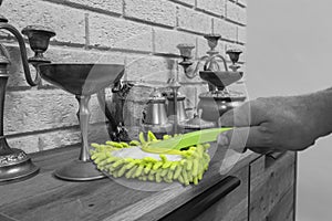 Man dusting wooden cabinet and pewter ornaments with a green microfibre dusting brush.