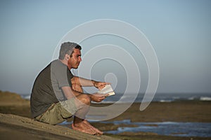 Man with Earphones and Book by Ocean