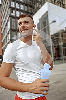 Man with earphones holding a plastic bottle