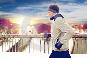 Man in earphones running along winter bridge
